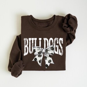 A brown sweatshirt with the word "BULLDOGS" printed on it, along with a soccer ball and a bow.