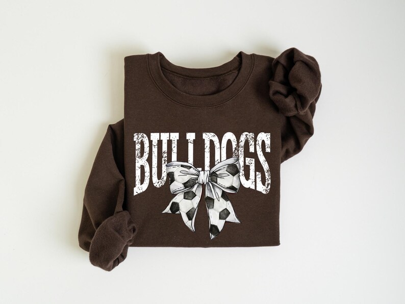 A brown sweatshirt with the word "BULLDOGS" printed on it, along with a soccer ball and a bow.