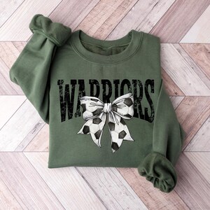 A green sweatshirt with a bow and the word "WARRIORS" printed on it.