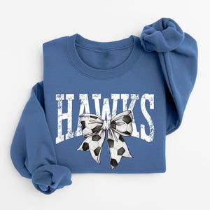 A blue sweatshirt with the word "HAWKS" printed on it, along with a bow design.