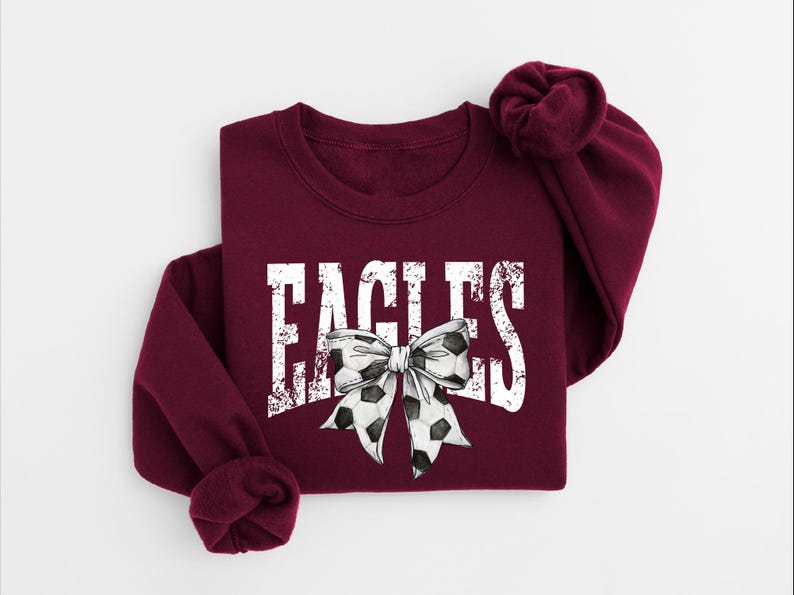 A burgundy sweatshirt with the word "EAGLES" printed on it, along with a bow design.