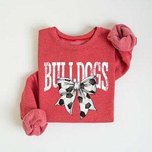 A red sweatshirt with the word "BUILTINS" printed on it, along with a bow design.