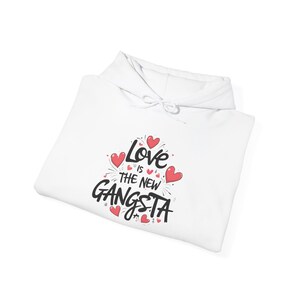 May include: White hoodie with a graphic print that says "Love is the new Gangsta" with pink hearts around the text.