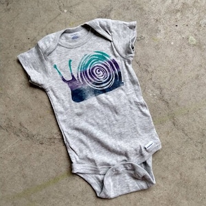 May include: Gray baby onesie with a colorful snail graphic. The snail is a dark purple, teal, and green color.