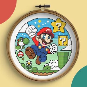 以下が含まれることがあります： スーパーマリオブラザーズのビデオゲームの、マリオのピクセル化された画像が特徴のクロスステッチ刺繍枠。 マリオはヨッシー、クエスチョンマークの星、緑色のパイプと一緒にジャンプしている様子が描かれています。 背景は星のある青色です。