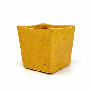 May include: A square, yellow ceramic planter with a speckled texture. The planter has a slightly flared top and a solid base. The color is a warm, mustard yellow, and the overall design is simple and modern.