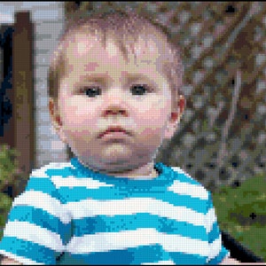 May include: A close-up portrait of a young child with light brown hair wearing a blue and white striped shirt. The child is looking directly at the camera with a serious expression.