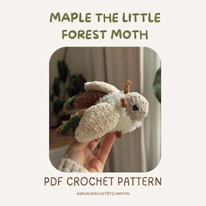 Peut inclure: Un jouet de papillon de nuit au crochet fait à la main, de couleur crème, marron et vert. Le papillon a des ailes duveteuses et un corps détaillé. Le texte "MAPLE THE LITTLE FOREST MOTH" et "PDF CROCHET PATTERN" sont affichés.