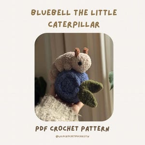 May include: A crocheted caterpillar toy in beige sits atop a blue crocheted ball with green leaves. The text "BLUEBELL THE LITTLE CATERPILLAR" and "PDF CROCHET PATTERN" are displayed above and below the toy.