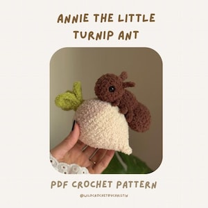Könnte beinhalten: Ein gehäkeltes Plüschtier, das eine braune Ameise auf einer cremefarbenen Rübe mit hellgrünen Blättern zeigt. Der Text ANNIE THE LITTLE TURNIP ANT und PDF CROCHET PATTERN steht über und unter dem Bild des handgefertigten Stofftieres.