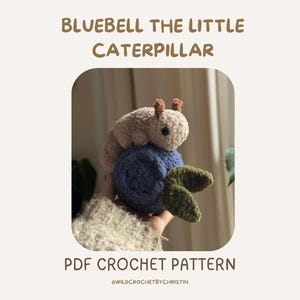 Könnte beinhalten: Ein gehäkeltes Raupenspielzeug in Beige, das auf einem blauen gehäkelten Ball mit grünen Blättern sitzt. Der Text "BLUEBELL THE LITTLE CATERPILLAR" und "PDF CROCHET PATTERN" werden oberhalb und unterhalb des Bildes angezeigt.