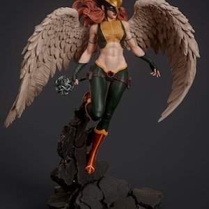 May include: A detailed figurine of a superhero with feathered wings, wearing a yellow and green costume with a gold helmet. The figurine is standing on a rocky base.
