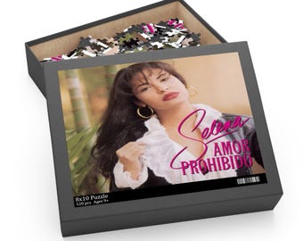 Może przedstawiać: Puzzle składające się ze 120 elementów przedstawiające portret Seleny, popularnej piosenkarki latynoskiej, z tytułem "Selena Amor Prohibido" w różowych literach.
