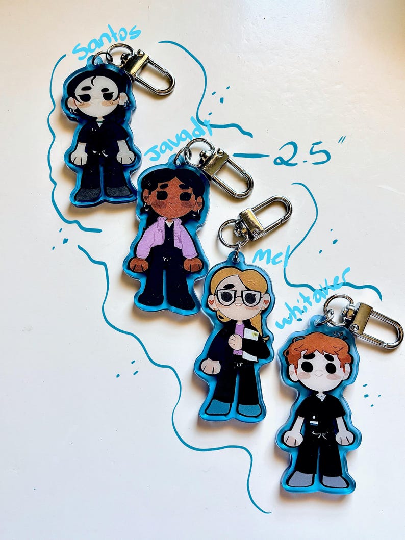 May include: Four cartoon character keychains with blue outlines and silver clasps. Each keychain is approximately 2.5 inches tall. The characters are dressed in various outfits, including a black suit, a pink jacket, and a black uniform. The names "Santos", "Javadi", "Mc", and "Whitaker" are written above or near each character.