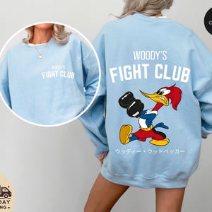 a woman wearing a blue woody's fight club sweatshirt