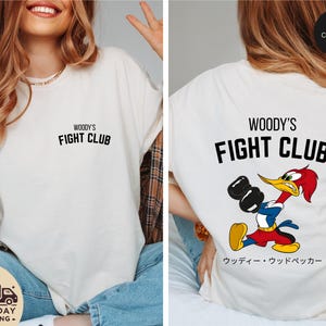 a woman wearing a woody's fight club t - shirt