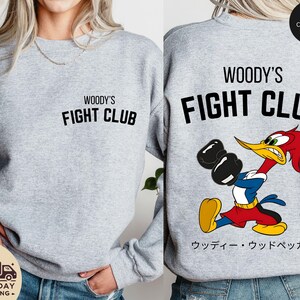 a woman wearing a woody's fight club sweatshirt