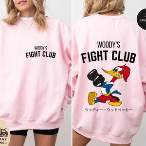 a woman wearing a pink woody's fight club sweatshirt