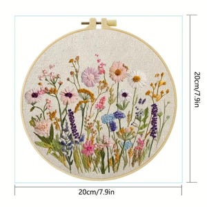 Op de afbeelding: Een ronde borduurring met een kleurrijk bloemenontwerp. De geborduurde bloemen zijn roze, paars, wit en geel, met groene bladeren. De ring heeft een diameter van 20 cm.