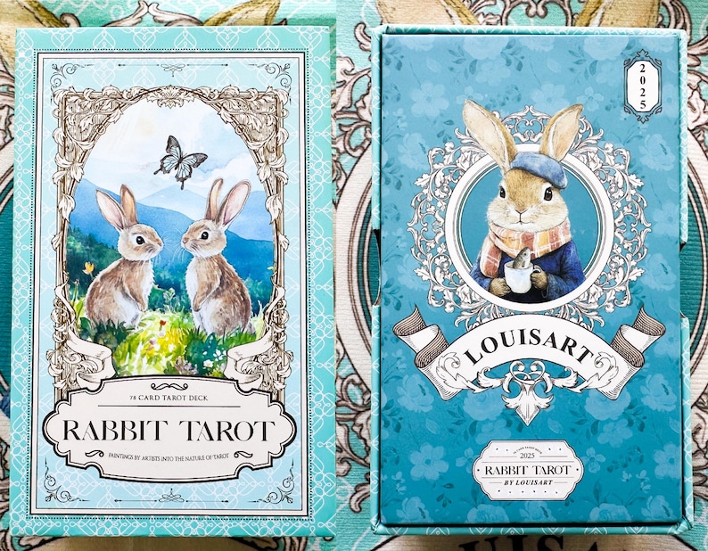 K&ouml;nnte beinhalten: Ein Rabbit Tarot Kartenspiel in einer t&uuml;rkisfarbenen Box. Die Vorderseite der Box zeigt eine Kaninchen-Illustration mit dem Text "RABBIT TAROT" und "78 CARD TAROT DECK". Die Box-Art beinhaltet einen Schmetterling und zwei Kaninchen. Die Box hat auch den Text "LOUISART".