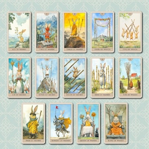 K&ouml;nnte beinhalten: Ein Tarotkartenspiel mit skurrilen Illustrationen von Kaninchen in verschiedenen Rollen, wie K&ouml;nig, K&ouml;nigin und Ritter. Die Karten sind mit Titeln wie "Stab-Ass" und "Zehn der St&auml;be" beschriftet und vor einem hellblauen, gemusterten Hintergrund angeordnet.
