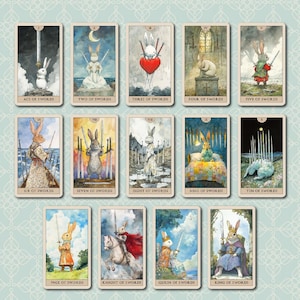K&ouml;nnte beinhalten: Ein Tarotkartenspiel mit Illustrationen von Kaninchen in verschiedenen Posen, die jeweils Schwerter halten. Die Karten sind mit Titeln wie "Schwert-Ass", "Zwei der Schwerter" und "K&ouml;nig der Schwerter" beschriftet. Das Wort "Schwerter" steht oben.