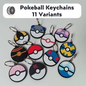 Op de afbeelding: Een verzameling van elf verschillende Pokeball-sleutelhangers. Elke sleutelhanger heeft een cirkelvormig ontwerp met verschillende kleurenschema's, waaronder rood, wit, zwart, blauw, geel en roze. De sleutelhangers hebben zilveren sleutelringen. De tekst "Pokeball Keychains 11 Variants" staat bovenaan.