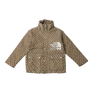 Peut inclure: Une veste à manches longues beige et marron avec un motif monogramme répétitif. La veste présente un col montant, une fermeture à boutons sur le devant avec des détails argentés et deux poches. Le texte THE NORTH FACE GUCCI est brodé en blanc.
