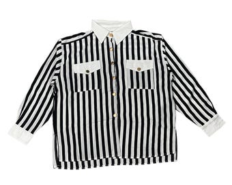 May include: A black and white striped button-down shirt with a white collar and cuffs. The shirt has two chest pockets with gold-colored buttons and a vertical stripe pattern. The long-sleeved shirt is a classic style.