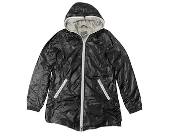 May include: A black hooded jacket with a full-length zipper and two zippered pockets. The jacket has a shiny, water-resistant exterior and a gray interior lining. White trim accents the zipper and pockets. The jacket is designed for outdoor wear.