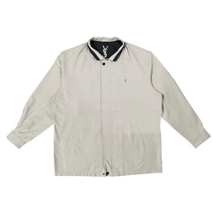 Puede incluir: Chaqueta beige claro con cuello negro y pequeño logo en el pecho. La chaqueta tiene cierre de cremallera y dos bolsillos delanteros. El cuello es negro por dentro. La chaqueta es de color neutro y adecuada para varios conjuntos.