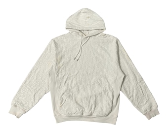 May include: Off-white hoodie with a drawstring hood and a kangaroo pocket. The sweatshirt features a repeating pattern across the fabric. The cuffs and hem are ribbed. The hoodie is made of a soft, textured material.