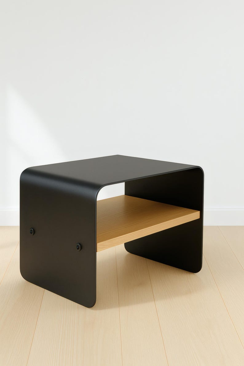 A black metal nightstand with a light wood shelf, shown at an angle on a light wood floor against a white wall.