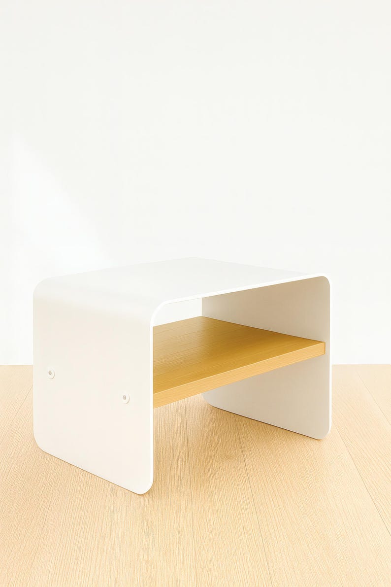 A white metal nightstand with a light wood shelf, shown at an angle on a light wood floor against a white wall.