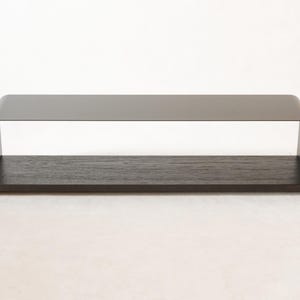 May include: A contemporary coffee table featuring a dark grey metal frame and a dark wood shelf. The table has a rectangular form with rounded corners and measures approximately 122 cm long, 30 cm wide, and 36 cm high.