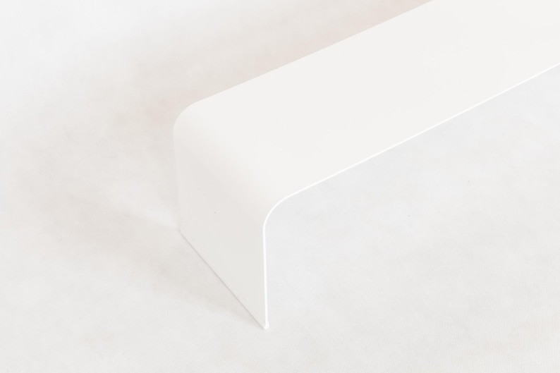 May include: A minimalist, white, modern-style table or shelf with a rounded corner. The object is set against a white background, creating a clean and simple aesthetic. The design is sleek and contemporary.