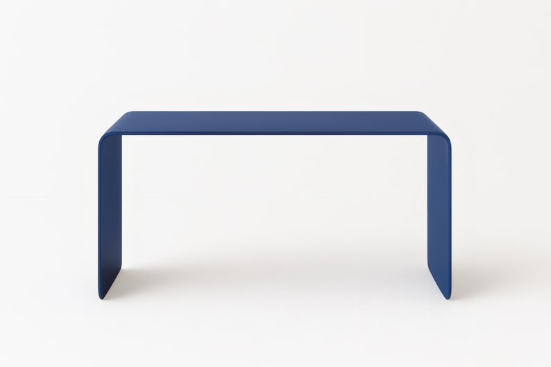Front view of an ultramarine blue minimalist bent metal table against a solid white background.