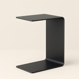 A black C-shaped metal side table is shown from a slight angle against a light beige background.