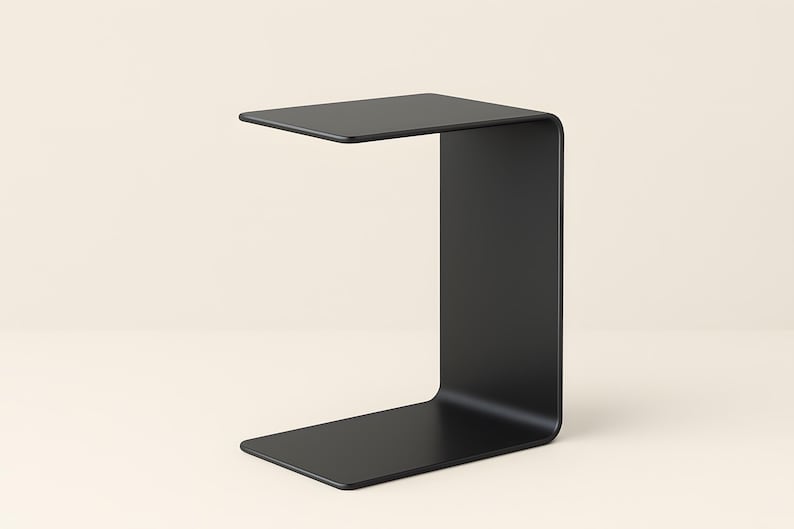 A black C-shaped metal side table is shown from a slight angle against a light beige background.
