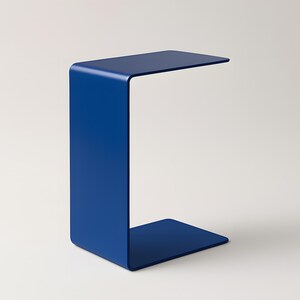 A blue C-shaped metal side table is shown from a slight angle against a light gray background.