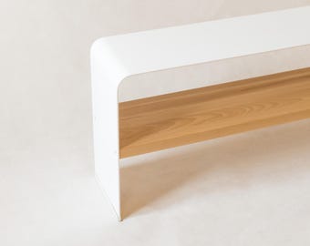 May include: A modern bench with a white top and a natural wood base. The bench has a minimalist design with clean lines and a simple, elegant aesthetic. The wood base provides a warm contrast to the white top.