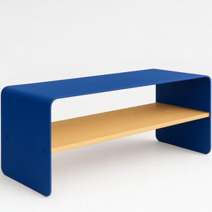 A blue metal bench with rounded corners and a light wood shelf, shown at an angle against a white background.