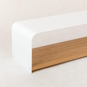 Può includere: Mensola rettangolare moderna con parte superiore bianca curva e base in legno naturale. Il design minimalista e le linee pulite la rendono adatta all'arredamento e all'esposizione di oggetti.
