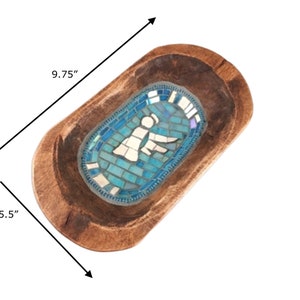 May include: A wooden dough bowl with a blue mosaic design featuring an angel. The bowl measures 9.75 inches long and 5.5 inches wide.