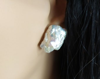May include: A pair of iridescent white baroque pearl earrings. The pearls are irregular in shape and have a natural, organic look.