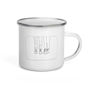 Peut inclure: Mug en émail blanc avec un dessin au trait noir de deux paires de jambes et de bottes. Le dessin est à l'intérieur d'un rectangle.