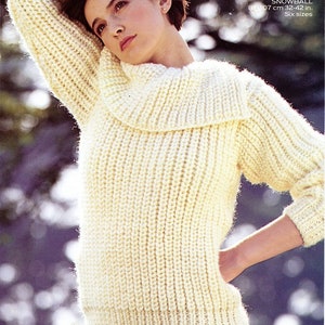 Könnte beinhalten: Ein weißer Strickpullover mit einem breiten, gefalteten Rollkragen. Der Pullover ist aus einem dicken Garn gestrickt und hat eine gerippte Struktur. Das Model trägt einen schwarzen Rock.