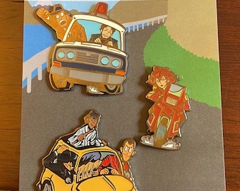 May include: Three enamel pins featuring cartoon illustrations of thieves in cars. The first pin shows a white car with two thieves inside. The second pin shows a yellow car with four thieves inside. The third pin shows a thief riding a motorcycle. The pins are on a grey background with the text "3 Thieves in a Small Italian Car Art By LUCA BAUMGART @lucabaumgART"