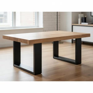 May include: A rectangular wooden table with a light brown surface and black U-shaped legs. The table is made of solid wood and has a modern design. The table is approximately 60 inches long and 30 inches wide.