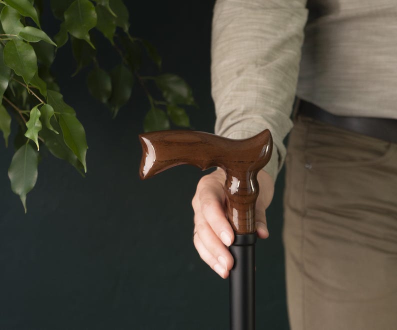 Op de afbeelding: Een wandelstok met een donkerbruine houten handgreep en een zwarte schacht.